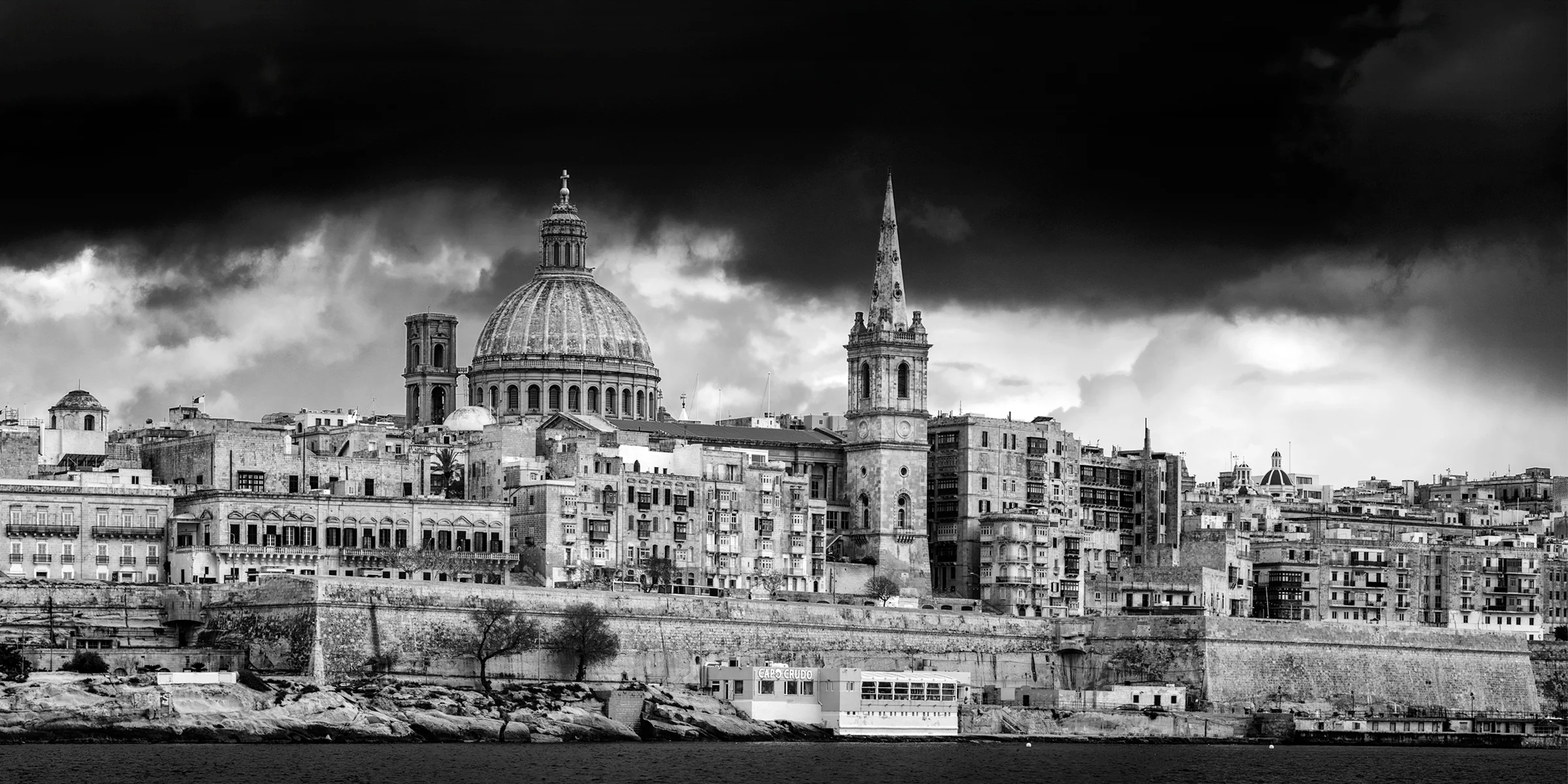 Valletta skyline at dawn, Malta. Black-and-white panoramic view of the Carmelite Church dome and St Paul's Pro-Cathedral spire.